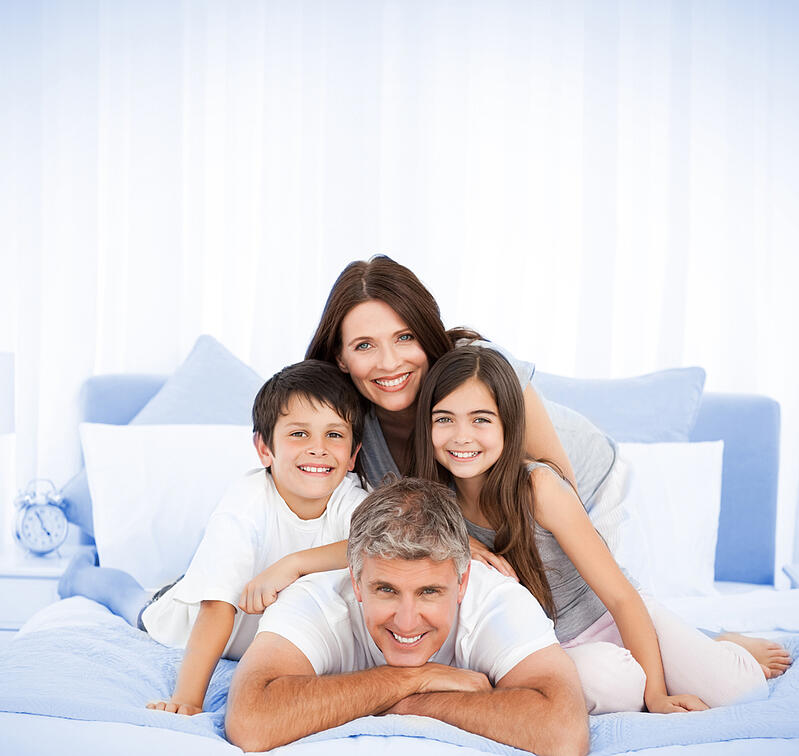 Happy family portrait in bed with two parents and brother sister